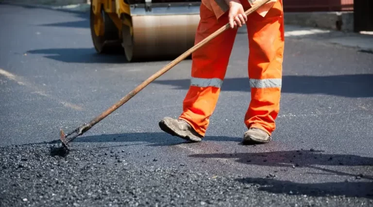person adding asphalt to road